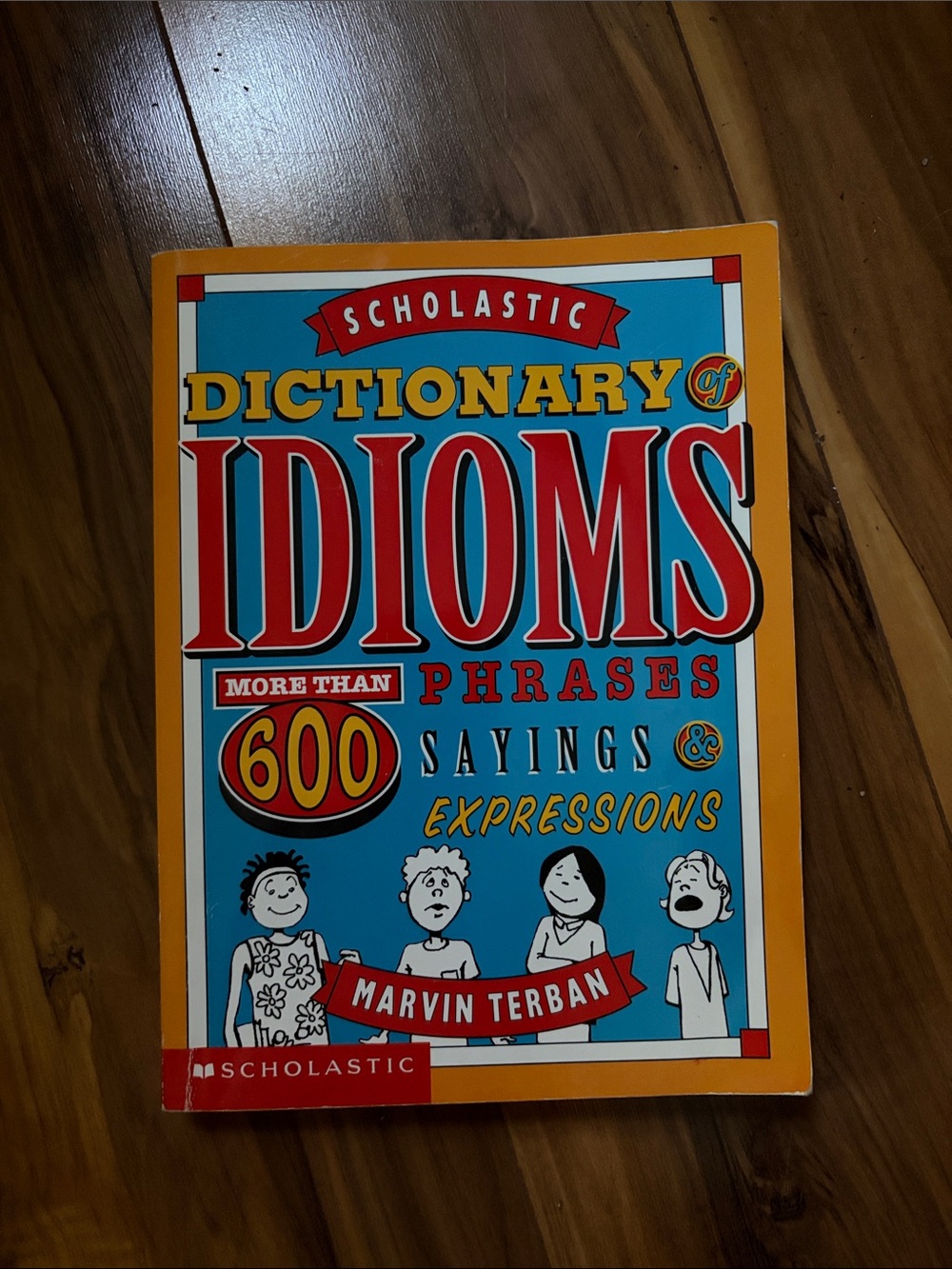 Scholastic Idioms Guide — Blue & Orange Illustrated Cover